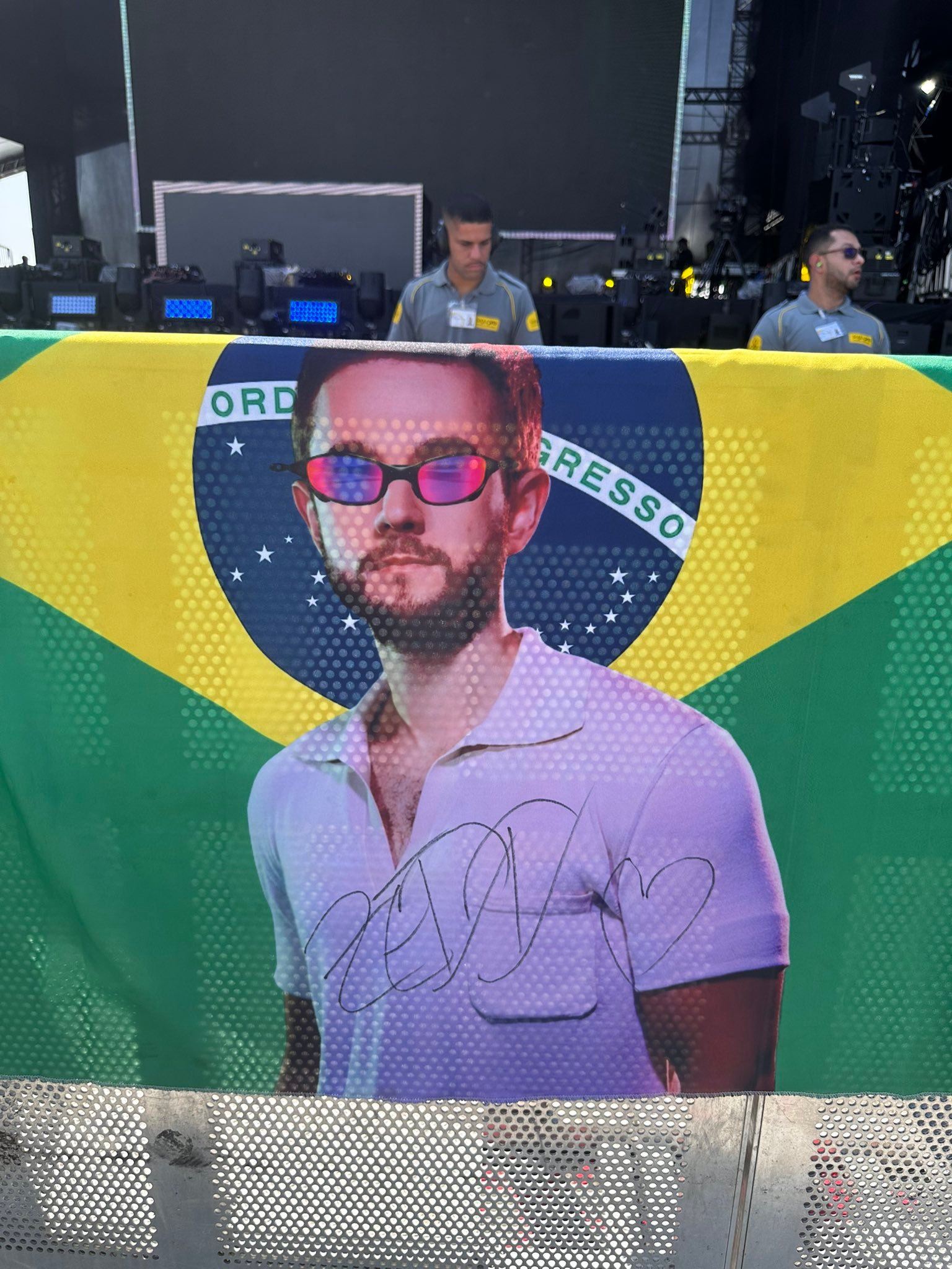 Bandeira da Zedd Brasil no Lollapalooza Brasil 2025, com o retrato de Zedd e a assinatura dele em marcador preto.